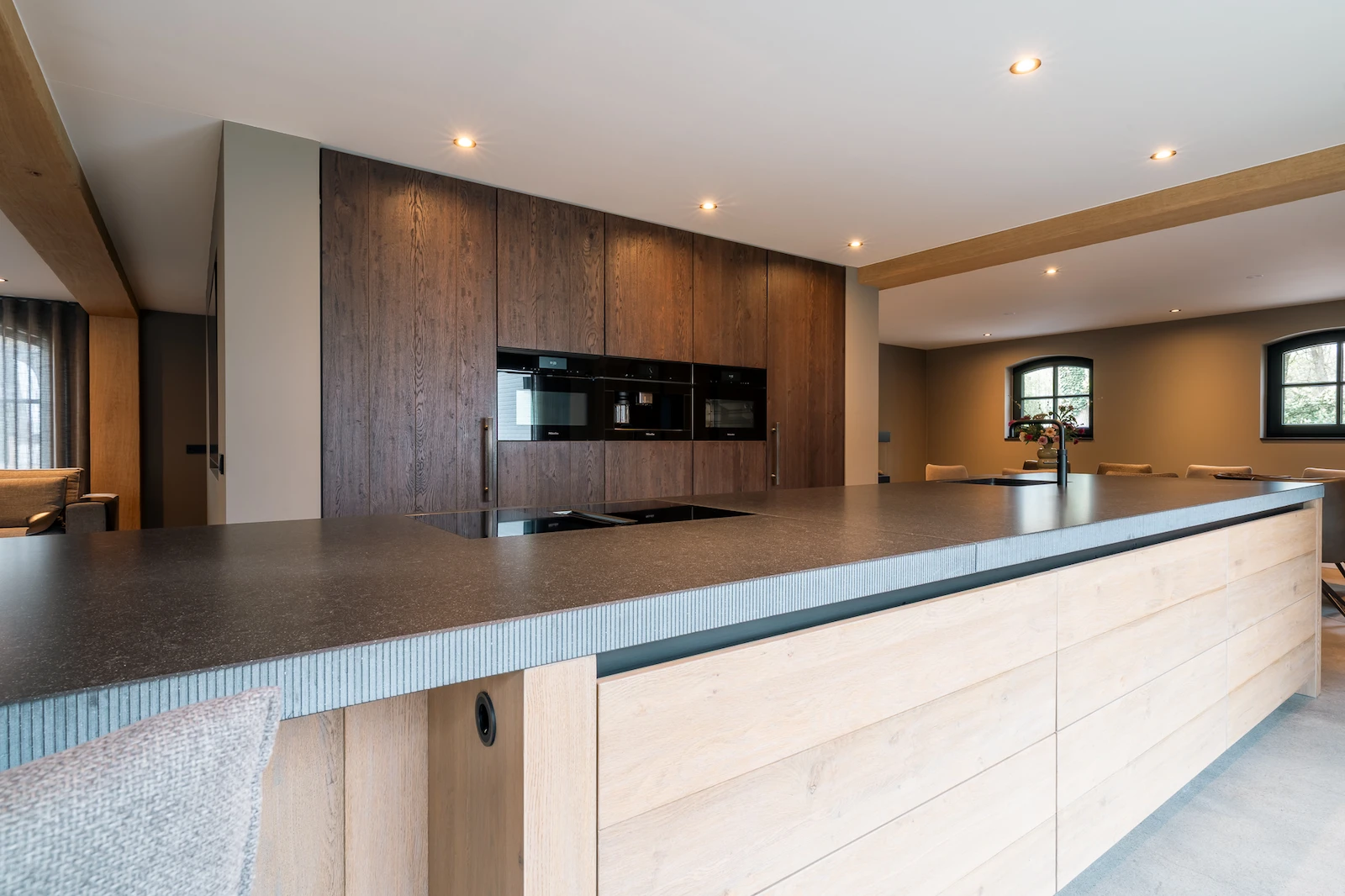 Keuken in warm hout met lang kookeiland onder balkenplafond